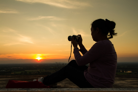 Uthai Thani, Thailand - December, 17, 2016 : Unidentified Silhouette of photographer taking pictures with camera in sunset sky at Wat Sangkat Rattana Khiri on Khao Sakae Krang mountain in Uthai Thani, Thailandのeditorial素材