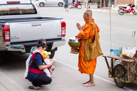 Uthai Thani, Thailand - December, 17, 2016 : Unidentified monks receive food offering from people in the morning market.Offering food is one of most common rituals in Buddhism.のeditorial素材