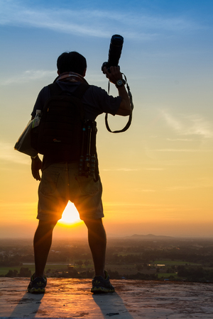 Uthai Thani, Thailand - December, 17, 2016 : Unidentified Silhouette of photographer taking pictures with camera in sunset sky at Wat Sangkat Rattana Khiri on Khao Sakae Krang mountain in Uthai Thani, Thailandのeditorial素材