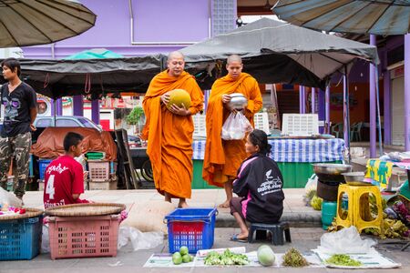 Uthai Thani, Thailand - December, 17, 2016 : Unidentified monks receive food offering from people in the morning market.Offering food is one of most common rituals in Buddhism.のeditorial素材