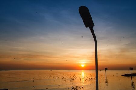 Silhouette of streetlight with beautiful sunset twilight sky at the seaの写真素材