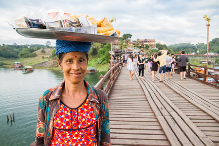 Kanchanaburi,Thailand - December, 25, 2016 : Unidentified asian women selling fried snack on the wooden bridge over the river in sunset at Sangkhlaburi, Mon Bridge is the longest bridge in Thailandのeditorial素材