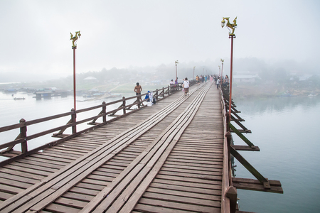 Kanchanaburi,Thailand-December,26,2016:Unidentified Tourist walk on the wooden bridge over the river in morning with fog and veil of mist at Sangkhlaburi, Mon Bridge is the longest bridge in Thailandのeditorial素材