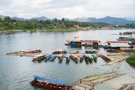 Kanchanaburi, Thailand - December, 25, 2016 : Top view of the House floating port boat tour on the wooden bridge (Mon Bridge) over the river in sunset at Sangkhlaburi, Mon Bridge is the longest bridge in Thailand.のeditorial素材
