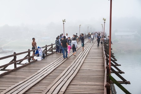 Kanchanaburi,Thailand-December,26,2016:Unidentified Tourist walk on the wooden bridge over the river in morning with fog and veil of mist at Sangkhlaburi, Mon Bridge is the longest bridge in Thailandのeditorial素材