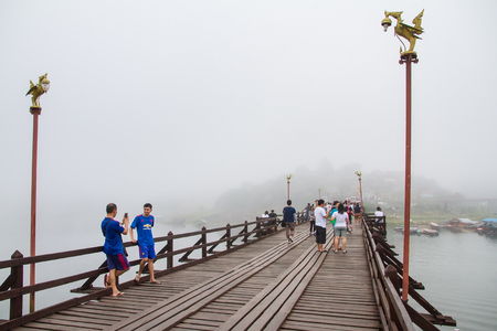 Kanchanaburi,Thailand-December,26,2016:Unidentified Tourist walk on the wooden bridge over the river in morning with fog and veil of mist at Sangkhlaburi, Mon Bridge is the longest bridge in Thailandのeditorial素材
