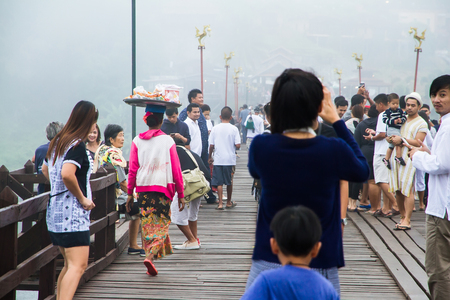 Kanchanaburi,Thailand-December,26,2016:Unidentified Tourist walk on the wooden bridge over the river in morning with fog and veil of mist at Sangkhlaburi, Mon Bridge is the longest bridge in Thailandのeditorial素材