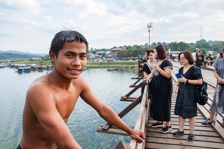 Kanchanaburi, Thailand - December, 26, 2016 : Unidentified Young boy jumping into river from wooden bridge (Mon Bridge) at Sangkhlaburi, Mon Bridge is the longest bridge in Thailand.のeditorial素材