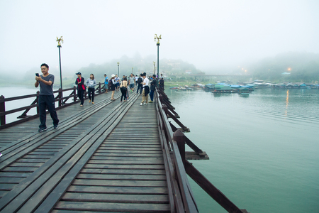 Kanchanaburi,Thailand-December,26,2016:Unidentified Tourist walk on the wooden bridge over the river in morning with fog and veil of mist at Sangkhlaburi, Mon Bridge is the longest bridge in Thailandのeditorial素材