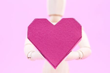 Wooden dummy holding paper box red heart shape on pink background with copy space for your text.Concept Valentine's Day, Day of loveの写真素材