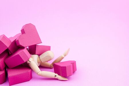 Wooden dummy was crushed by a pile of paper box red heart shape on pink background with copy space for your text.Concept Valentine's Day, Day of loveの写真素材
