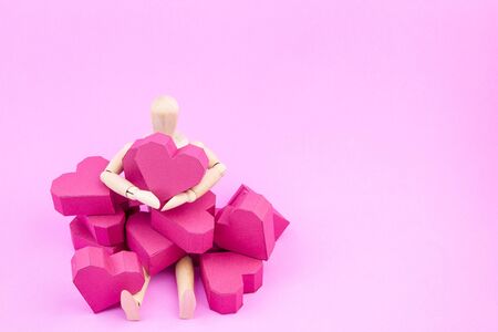 Wooden dummy holding paper box red heart shape on pink background with copy space for your text.Concept Valentine's Day, Day of loveの写真素材