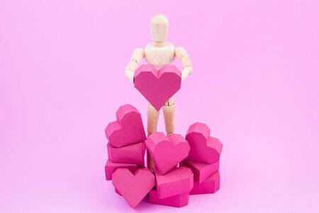 Wooden dummy holding paper box red heart shape on pink background with copy space for your text.Concept Valentine's Day, Day of loveの写真素材