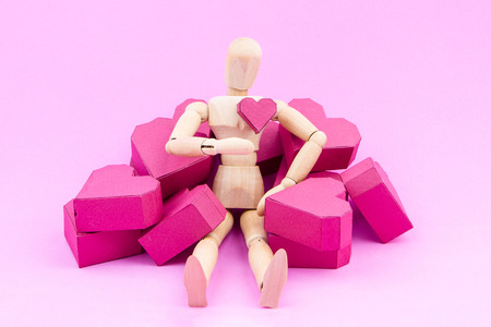 Wooden dummy and a pile of paper box red heart shape on pink background with copy space for your text.Concept Valentine's Day, Day of loveの写真素材