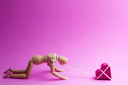 Wooden dummy chaining themselves to the paper box red heart shape on pink background with copy space for your text.Concept Valentine's Day, Day of love.の写真素材