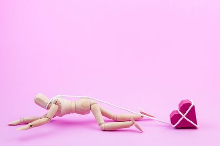 Wooden dummy chaining themselves to the paper box red heart shape on pink background with copy space for your text.Concept Valentine's Day, Day of love.の写真素材