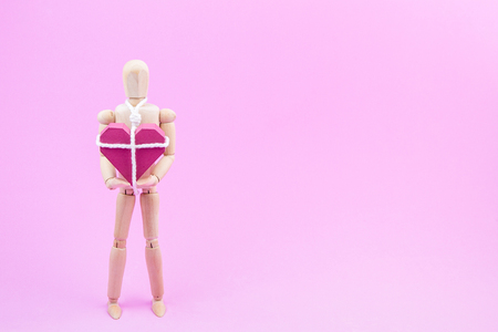 Wooden dummy chaining themselves to the paper box red heart shape on pink background with copy space for your text.Concept Valentine's Day, Day of love.の写真素材