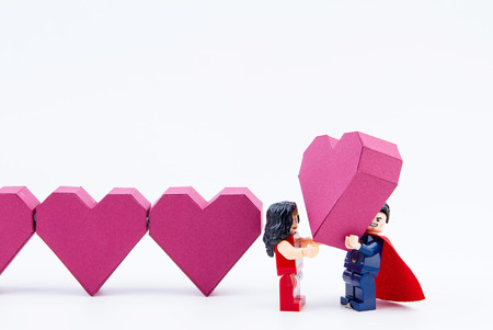 Nonthaburi, Thailand - January, 09, 2017 : Lego super man showing love give a paper box red heart shape to lego super woman on white background.Concept Valentine's Dayのeditorial素材