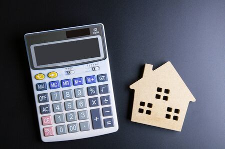 Wooden house toy and calculator on black background with copy space.Real estate concept, New house concept, Finance loan business conceptの写真素材