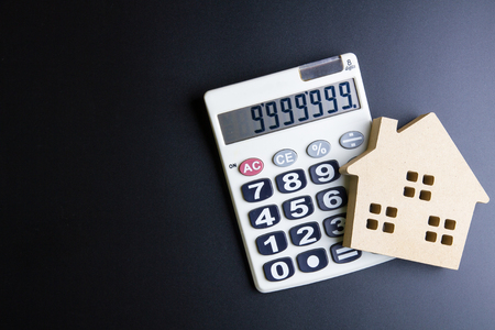 Wooden house toy and calculator on black background with copy space.Real estate concept, New house concept, Finance loan business conceptの写真素材