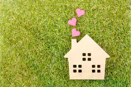 Wooden house toy and paper box red heart shape on ground green grass with copy space.Real estate concept, New house concept, Love house concept, Finance loan business conceptの写真素材