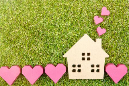 Wooden house toy and paper box red heart shape on ground green grass with copy space.Real estate concept, New house concept, Love house concept, Finance loan business conceptの写真素材