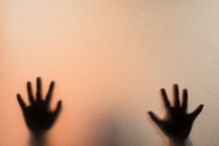Shadow blur hands of the Man behind frosted glass.Blurry hand abstraction.Halloween backgroundの写真素材