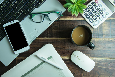 Top view of office stuff graphic design with pen mouse pad laptop wireless mouse smart phone and coffee cup on wooden table.Concept graphic design workplaceの写真素材