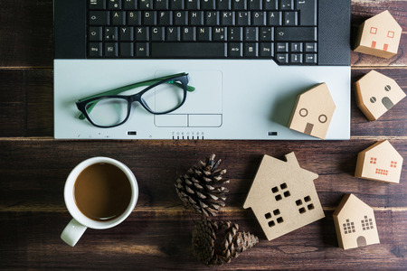 Top view of office stuff with laptop coffee cup and wooden house toy on wooden table.Concept workplace.Real estate concept, New house concept, Finance loan business conceptの写真素材