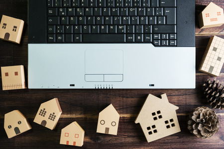 Top view of office stuff with laptop and Wooden house toy on wooden table.Concept workplace.Real estate concept, New house concept, Finance loan business conceptの写真素材