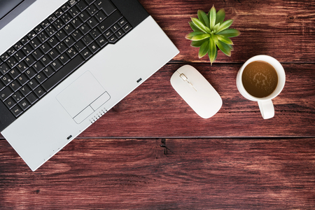 Top view of office stuff with laptop wireless mouse and coffee cup on wooden table.Concept workplaceの写真素材