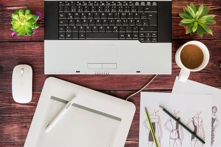 Top view of office stuff graphic design pen mouse pad with laptop wireless mouse paper sketch of a designer and coffee cup on wooden table.Concept graphic design workplaceの写真素材