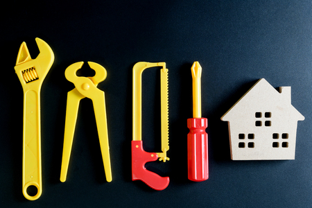 Wooden house toy and construction tools toy on black background with copy space.Home Repair concept, Repair maintenance concept, Renovation concept.の写真素材