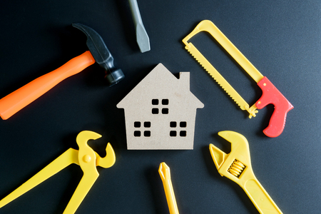 Wooden house toy and construction tools toy on black background with copy space.Home Repair concept, Repair maintenance concept, Renovation concept.の写真素材