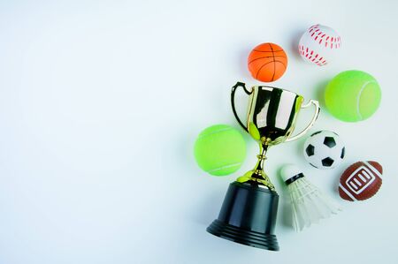 Golden trophy, Football toy, Baseball toy, Shuttlecock,Tennis ball, Basketball toy and Rugby toy isolated on white background with copy space.Concept winner of the sportの写真素材