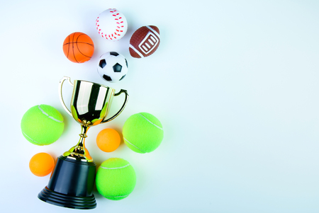 Golden trophy, Football toy, Baseball toy, Ping pong ball, Tennis ball, Basketball toy and Rugby toy isolated on white background with copy space.Concept winner of the sportの写真素材