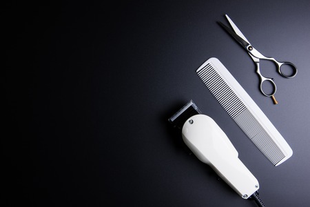 Stylish Professional Barber Scissors, White comb and White electric clippers on black background. Hairdresser salon concept, Hairdressing Set. Haircut accessories. Copy space image, flat layの写真素材