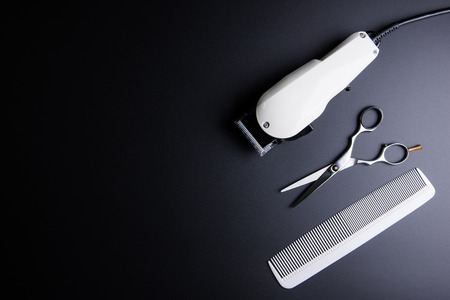 Stylish Professional Barber Scissors, White comb and White electric clippers on black background. Hairdresser salon concept, Hairdressing Set. Haircut accessories. Copy space image, flat layの写真素材