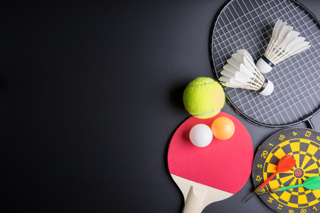 Darts, Racket table tennis, ping pong ball, Shuttlecocks, Badminton racket and Tennis ball on black background.Sport concept, Copy space image for your textの写真素材