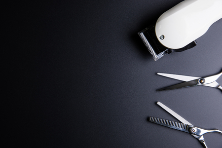 Stylish Professional Barber Scissors and White electric clippers on black background. Hairdresser salon concept, Hairdressing Set. Haircut accessories. Copy space image, flat layの写真素材