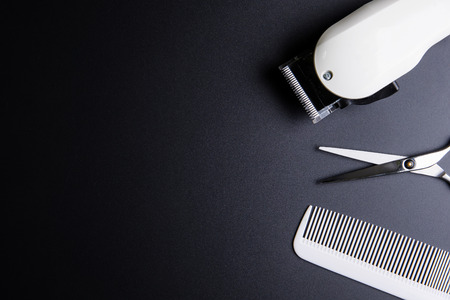 Stylish Professional Barber Scissors, White comb and White electric clippers on black background. Hairdresser salon concept, Hairdressing Set. Haircut accessories. Copy space image, flat layの写真素材