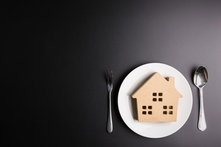 Wooden house in a white dish on black background with copy space image for your text.Real estate concept, New house concept, Finance loan business conceptの写真素材