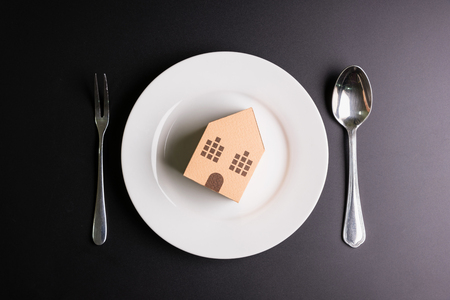 Paper house in a white dish on black background with copy space image for your text.Real estate concept, New house concept, Finance loan business conceptの写真素材