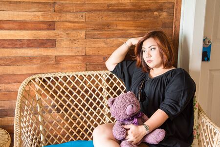 Chon Buri, Thailand - April, 27, 2017 : Portrait of Beautiful fat woman holding cute animal dolls on a wooden chair of Baan Sattahip Resort and sea background at Sattahip, Chon Buri, Thailand.のeditorial素材