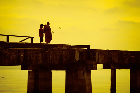 Chon Buri, Pattaya, Thailand - April, 29, 2017 : Buddhist monks are walking on a bridge in the evening sunset.Bridge of Temple Djittabhawan at Pattaya, Thailand.Long bridge extends into the sea.のeditorial素材