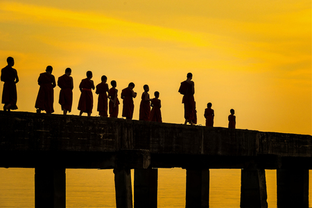 Chon Buri, Pattaya, Thailand - April, 29, 2017 : Buddhist monks are walking on a bridge in the evening sunset.Bridge of Temple Djittabhawan at Pattaya, Thailand.Long bridge extends into the sea.のeditorial素材