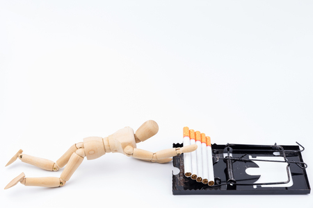 Wooden puppet caught in Mousetrap with cigarettes as bait.No Smoking Day background.Anti smoking.の写真素材