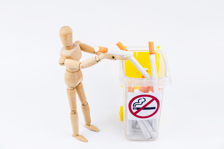Wooden puppet take the cigarettes to dumps.No Smoking Day background.Anti smokingの写真素材