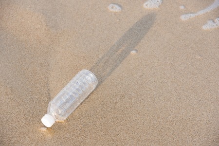 Empty plastic bottle on the beach in the morningの写真素材