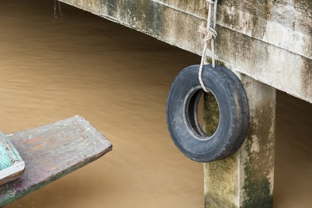 Old tires used as a bumper for boats or big truck tires used for bump stop in a commercial dockの写真素材